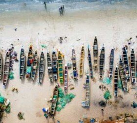 Different colored boats on sandy beach.